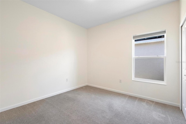spare room featuring baseboards and light colored carpet
