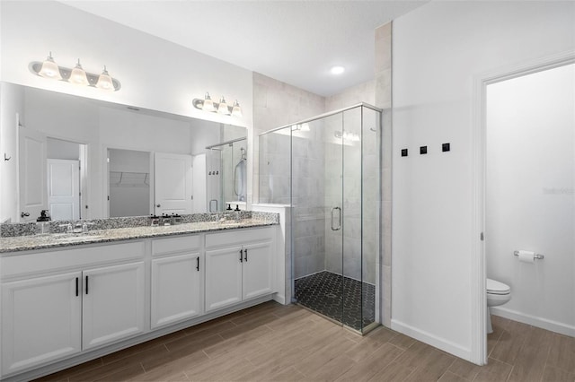 bathroom featuring wood tiled floor, baseboards, a shower stall, and toilet