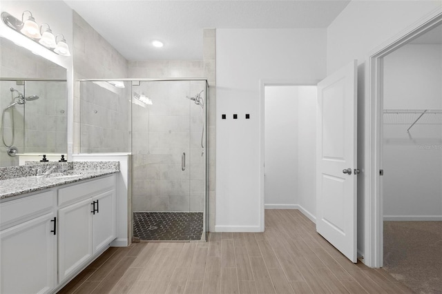 bathroom with wood finished floors, a stall shower, and a spacious closet