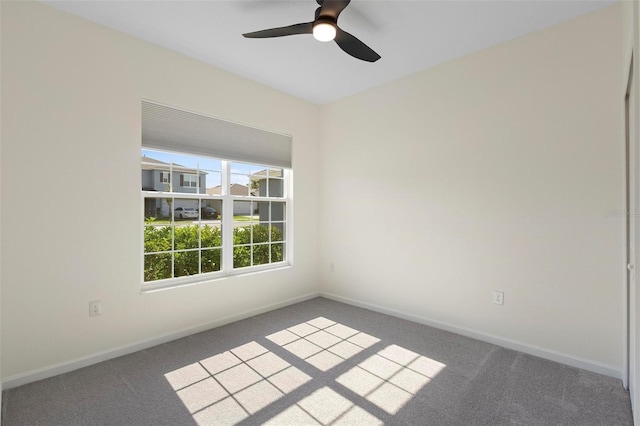 carpeted empty room featuring ceiling fan and baseboards