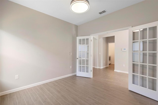 spare room with baseboards, visible vents, french doors, and wood finished floors