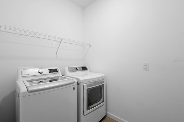 clothes washing area with separate washer and dryer, laundry area, and baseboards