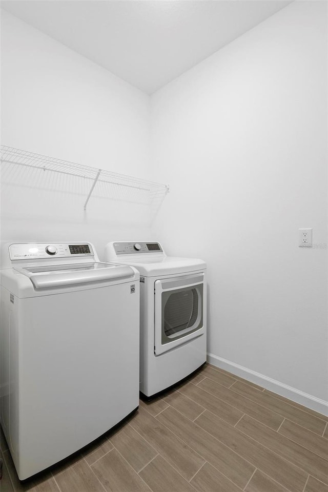 laundry room featuring baseboards, laundry area, wood finish floors, and independent washer and dryer