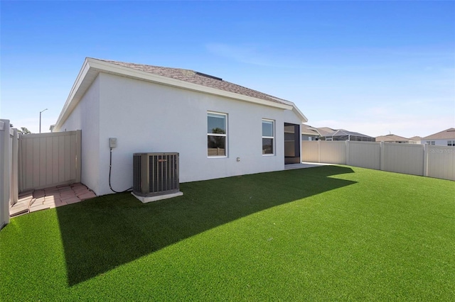 rear view of house with a lawn, a fenced backyard, stucco siding, and cooling unit