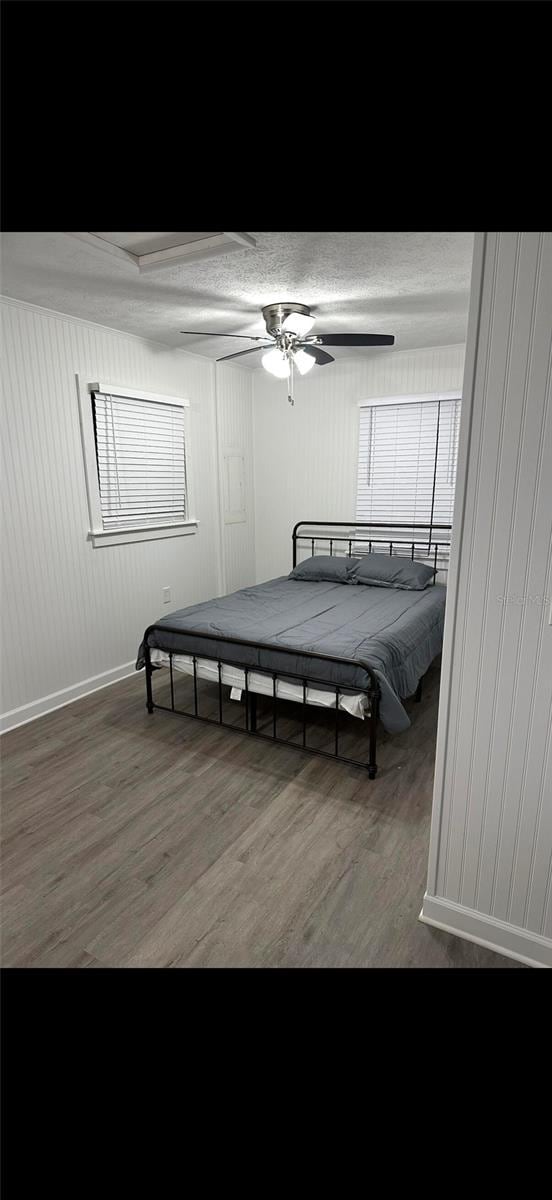 2902 Little Rd, Valrico, FL 33596 - bedroom with wood walls, baseboards, a ceiling fan, and wood finished floors