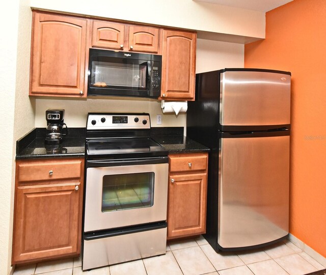 8112 Poinciana Blvd Unit 1809, Orlando, FL 32821 - kitchen featuring appliances with stainless steel finishes, dark stone counters, light tile patterned floors, and brown cabinetry