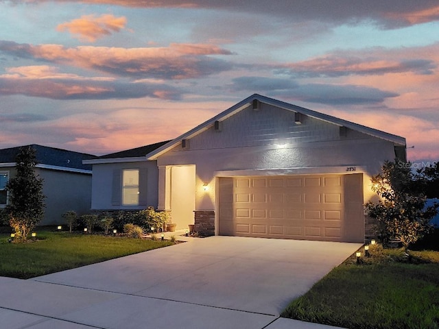 ranch-style house with a yard, a garage, concrete driveway, stone siding, and stucco siding