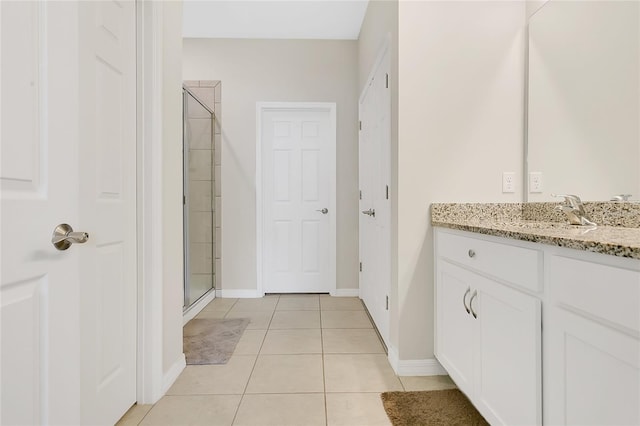 bathroom featuring vanity, a stall shower, baseboards, and tile patterned floors
