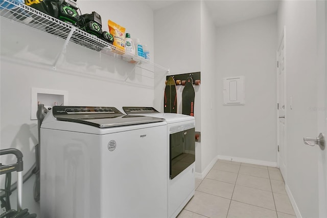 clothes washing area with independent washer and dryer, light tile patterned flooring, laundry area, and baseboards
