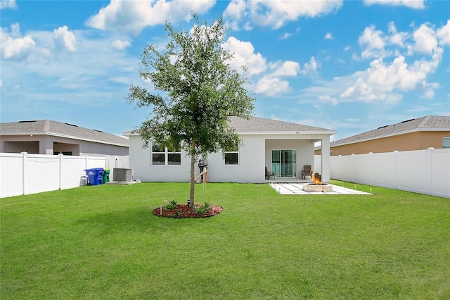 rear view of house with a lawn, a fenced backyard, a fire pit, and a patio area