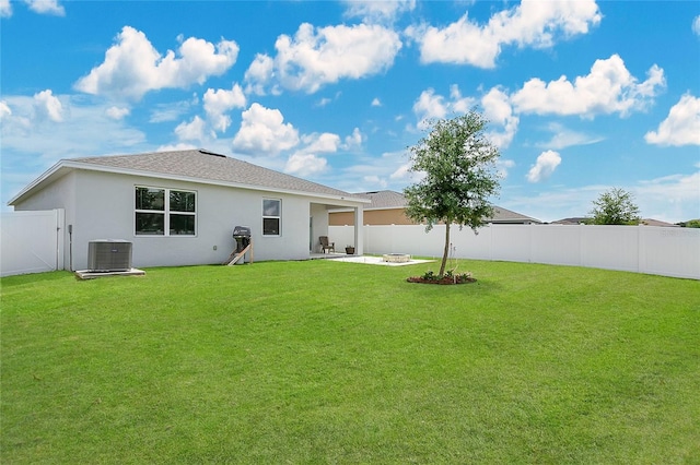 rear view of house with a patio, a fenced backyard, stucco siding, central AC unit, and a yard