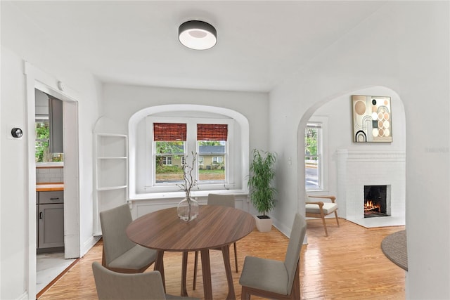 dining space featuring baseboards, light wood finished floors, and a fireplace