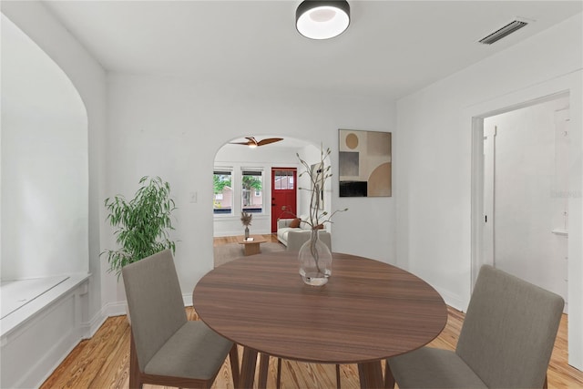 dining area with visible vents, arched walkways, and light wood-type flooring