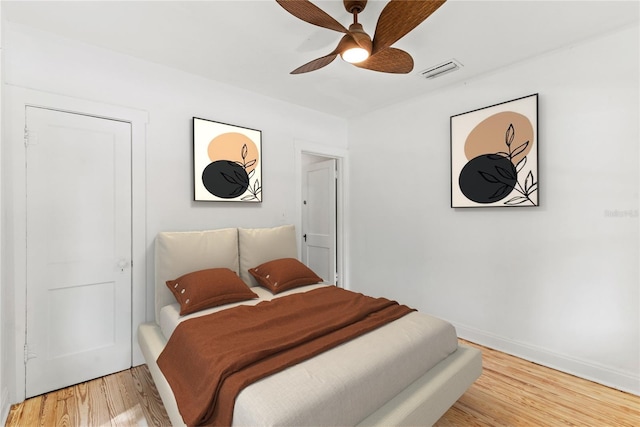 bedroom featuring baseboards, a ceiling fan, light wood finished floors, and visible vents
