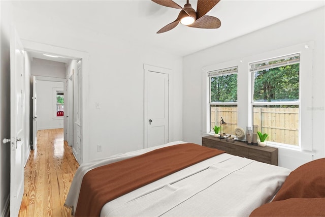 bedroom with light wood-style floors, a ceiling fan, and multiple windows