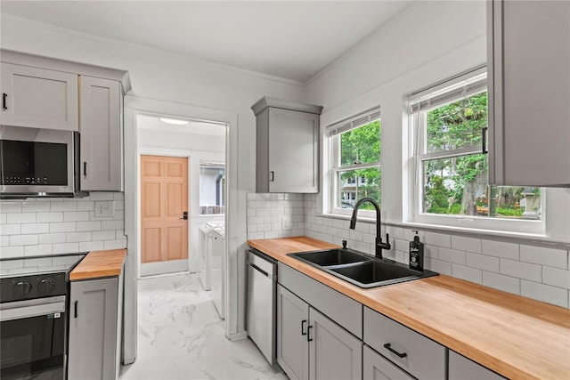 kitchen featuring gray cabinetry, a sink, wooden counters, and stainless steel appliances