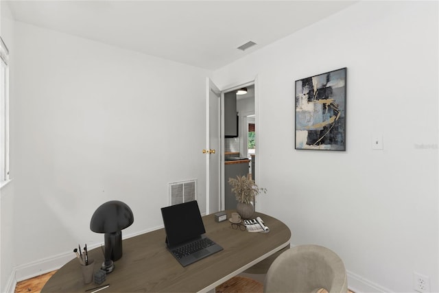 office space featuring baseboards, visible vents, and wood finished floors