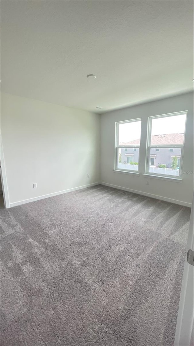 unfurnished room featuring carpet floors and baseboards