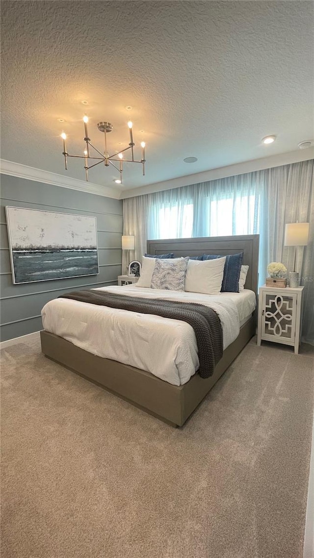 bedroom with carpet floors, a textured ceiling, crown molding, and an inviting chandelier