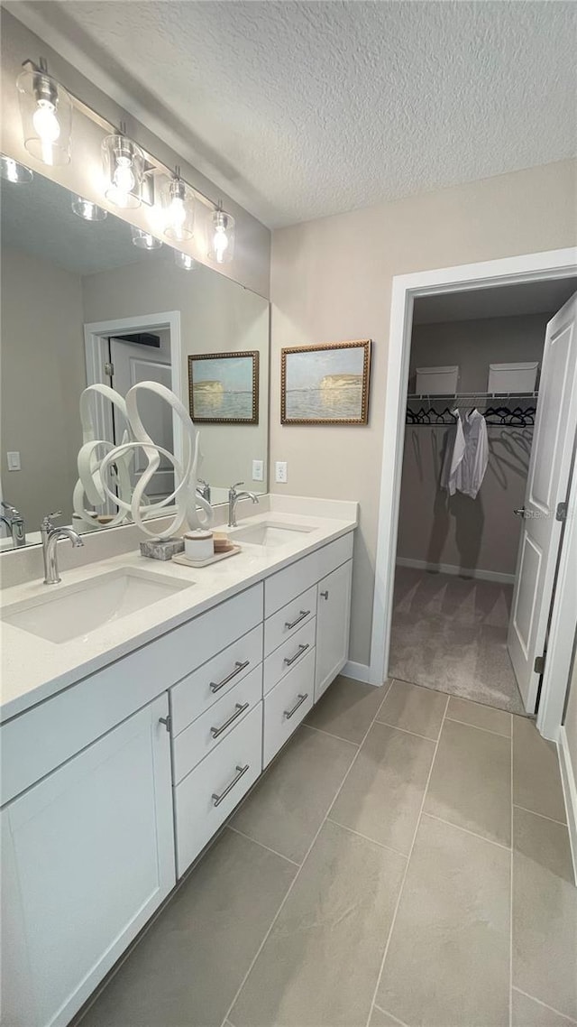 bathroom with a spacious closet, tile patterned flooring, a sink, and double vanity