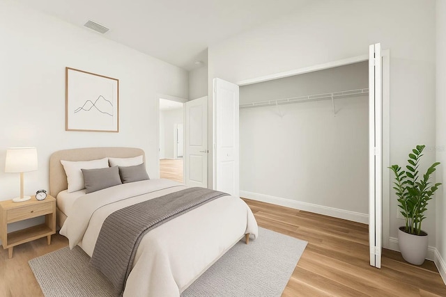 bedroom featuring light wood-type flooring, baseboards, and a closet