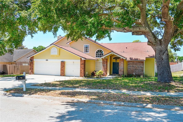traditional-style house featuring brick siding, an attached garage, fence, and concrete driveway