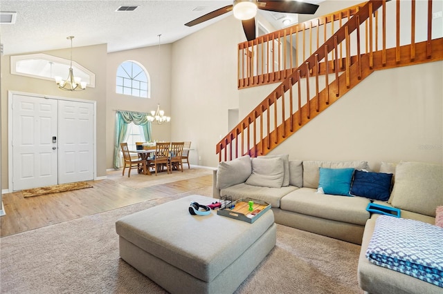 living area featuring high vaulted ceiling, visible vents, stairway, wood finished floors, and baseboards