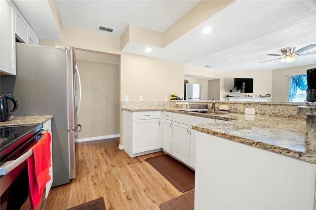 kitchen with white cabinets, light wood-type flooring, light stone counters, and visible vents