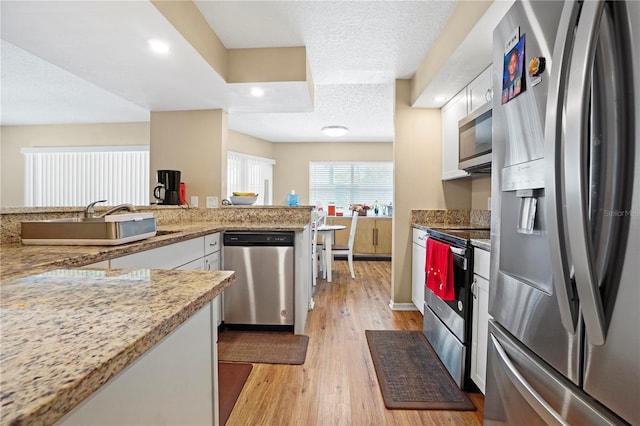 kitchen featuring stainless steel appliances, light wood-style floors, white cabinets, and a sink