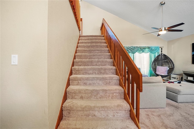 staircase with carpet flooring, vaulted ceiling, a ceiling fan, and a textured ceiling