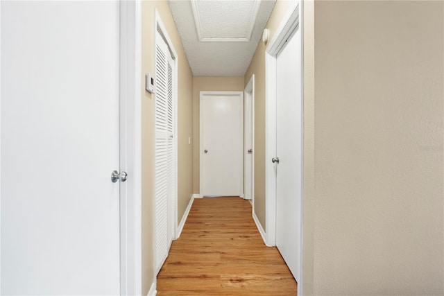 hallway featuring light wood-style flooring and baseboards