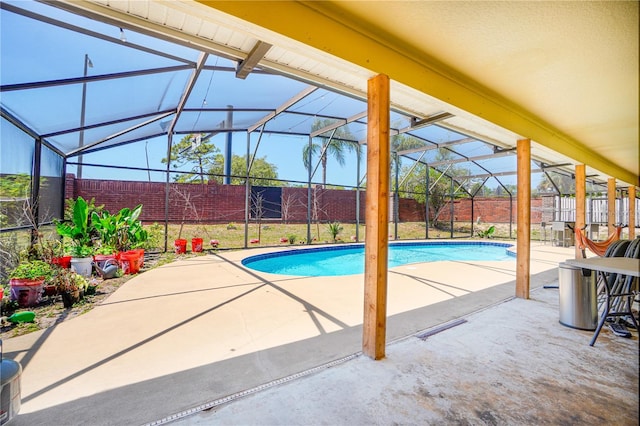 outdoor pool featuring a fenced backyard, glass enclosure, and a patio