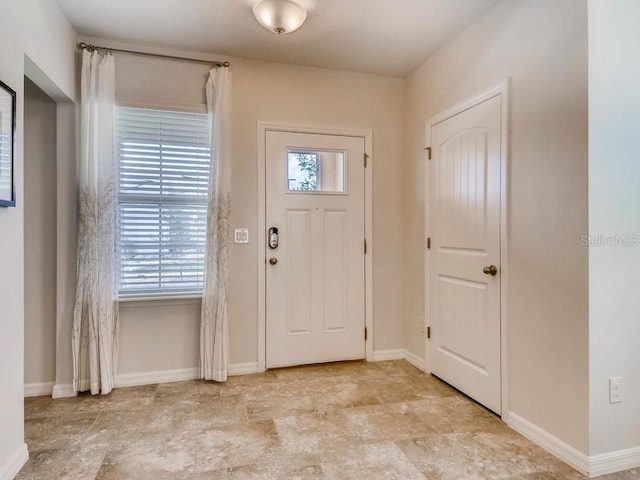 1550 Dalehurst Ln, Kissimmee, FL 34744 - foyer featuring stone finish floor, baseboards, and a healthy amount of sunlight