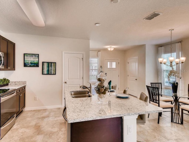1550 Dalehurst Ln, Kissimmee, FL 34744 - kitchen featuring visible vents, stainless steel range with electric stovetop, a sink, a textured ceiling, and dark brown cabinets