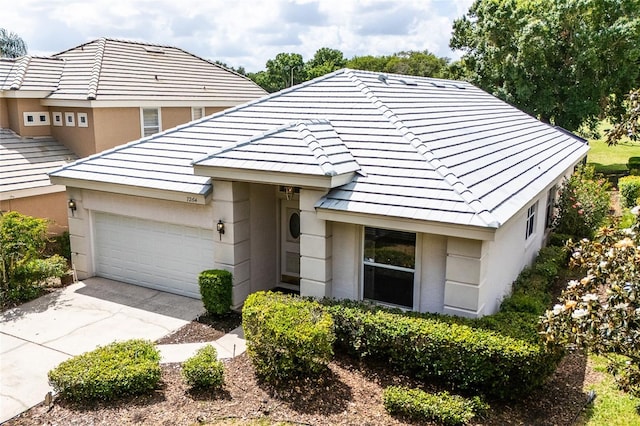 view of front of property with stucco siding, an attached garage, a tile roof, and concrete driveway