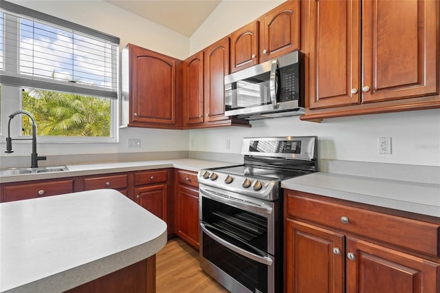 kitchen with appliances with stainless steel finishes, a sink, light countertops, and light wood-style flooring