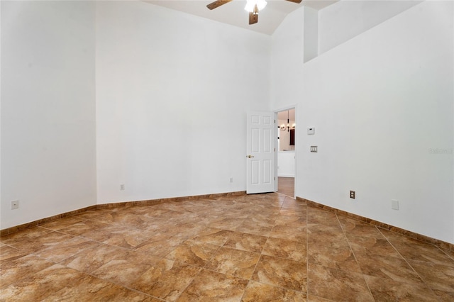 spare room with ceiling fan, baseboards, and a towering ceiling