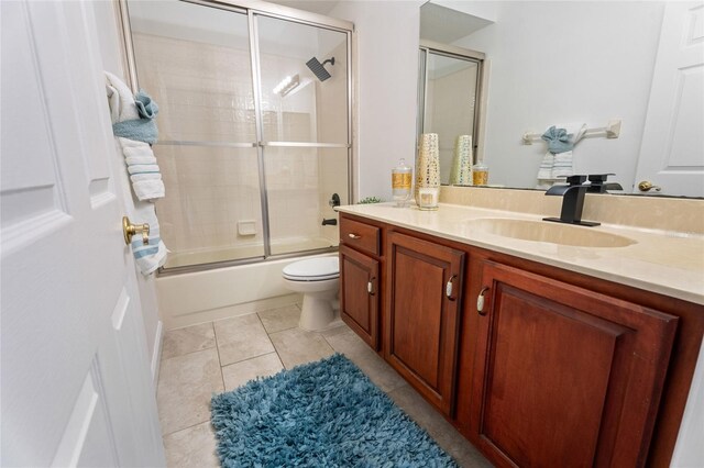 full bath featuring vanity, toilet, bath / shower combo with glass door, and tile patterned flooring