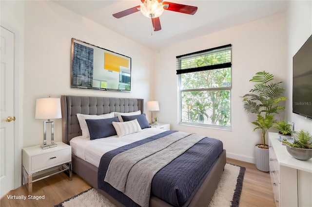 bedroom with light wood finished floors, baseboards, and a ceiling fan