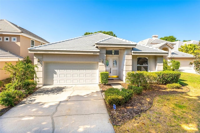 view of front of property with stucco siding, driveway, an attached garage, and a tile roof