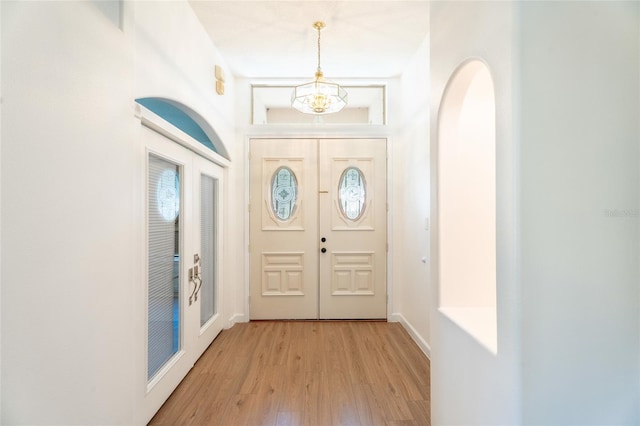 foyer featuring light wood-style flooring, baseboards, and a chandelier