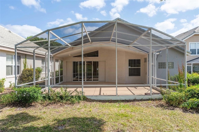rear view of property featuring ceiling fan, a yard, stucco siding, a patio area, and a lanai