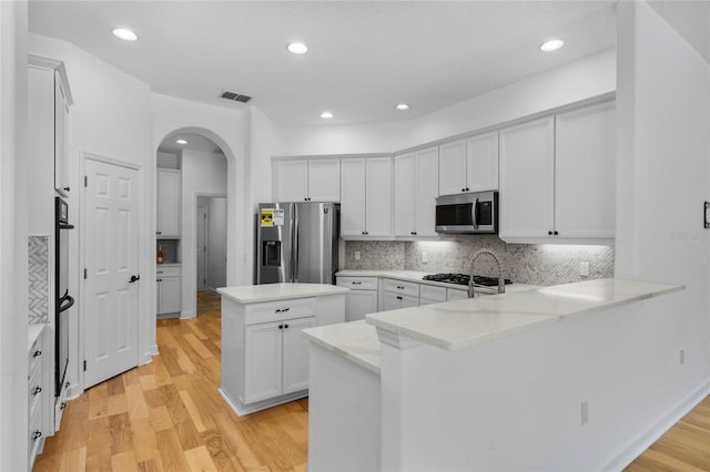1803 Glenbay Ct, Windermere, FL 34786 - kitchen featuring visible vents, a peninsula, light wood-style floors, arched walkways, and appliances with stainless steel finishes