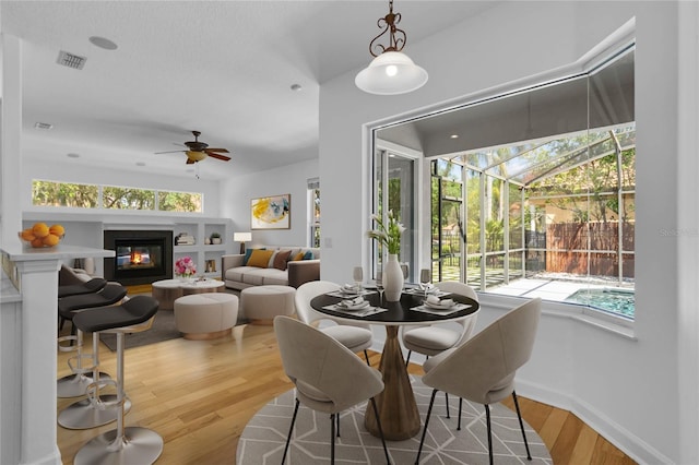 1803 Glenbay Ct, Windermere, FL 34786 - dining room with a glass covered fireplace, a ceiling fan, baseboards, wood finished floors, and visible vents