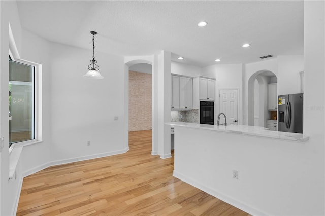 1803 Glenbay Ct, Windermere, FL 34786 - kitchen with oven, stainless steel fridge, light countertops, arched walkways, and white cabinetry