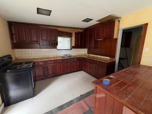 kitchen with arched walkways, tasteful backsplash, a sink, and electric range