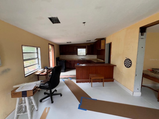 kitchen featuring dark countertops, a peninsula, baseboards, and a healthy amount of sunlight