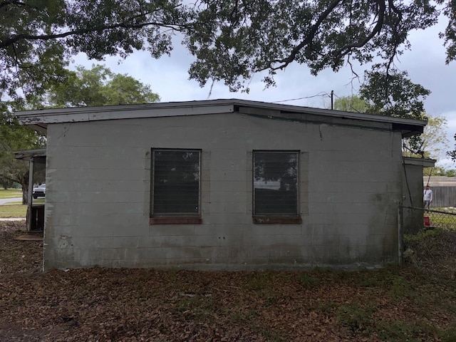 view of property exterior featuring concrete block siding and fence