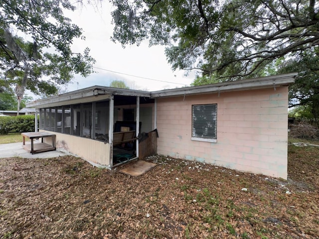 rear view of property with a sunroom and concrete block siding