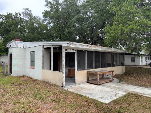 back of house featuring concrete block siding and a sunroom